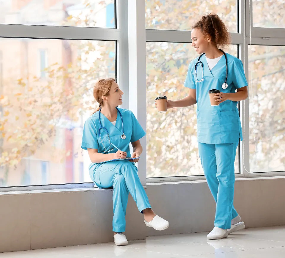Two clinicians taking a coffee break by a window